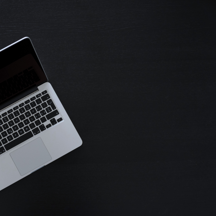 Birdseye view of a macbook on a black desk » admin by request