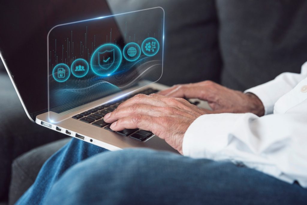 Close-up of hands typing on a laptop with holographic icons displaying security and analytics features.