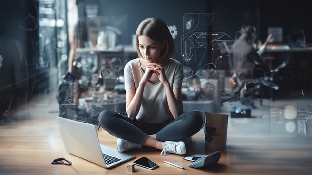 A woman sitting in front of two laptops protected with privileged access management » admin by request