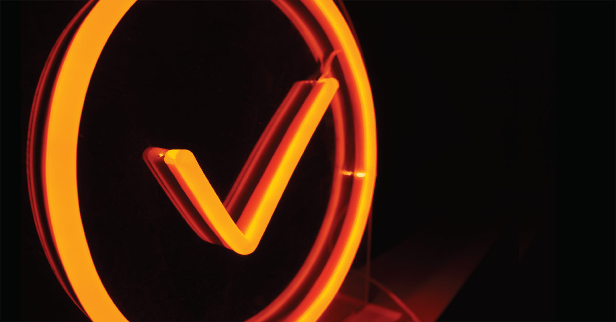 Admin By Request orange neon sign close up from the left side in a dark room.