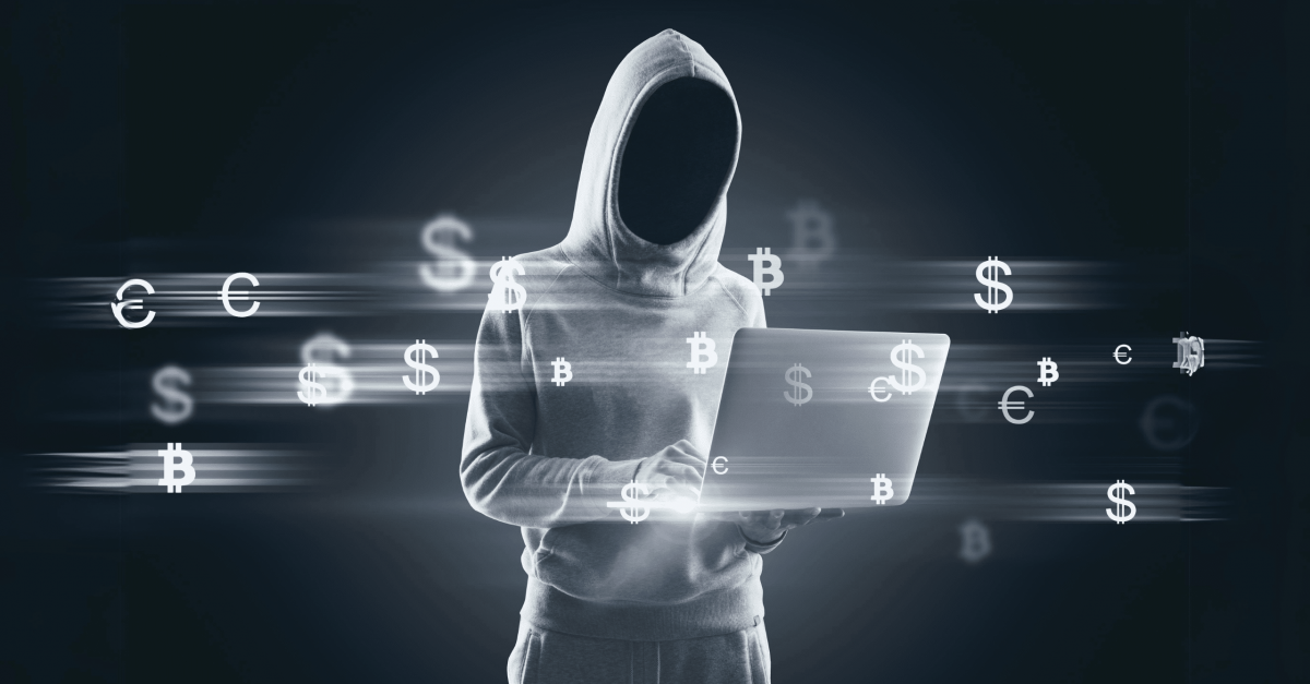 Hooded hacker holding a laptop while dollar signs swirl around them