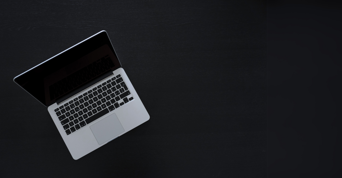 Birdseye view of a MacBook on a black desk