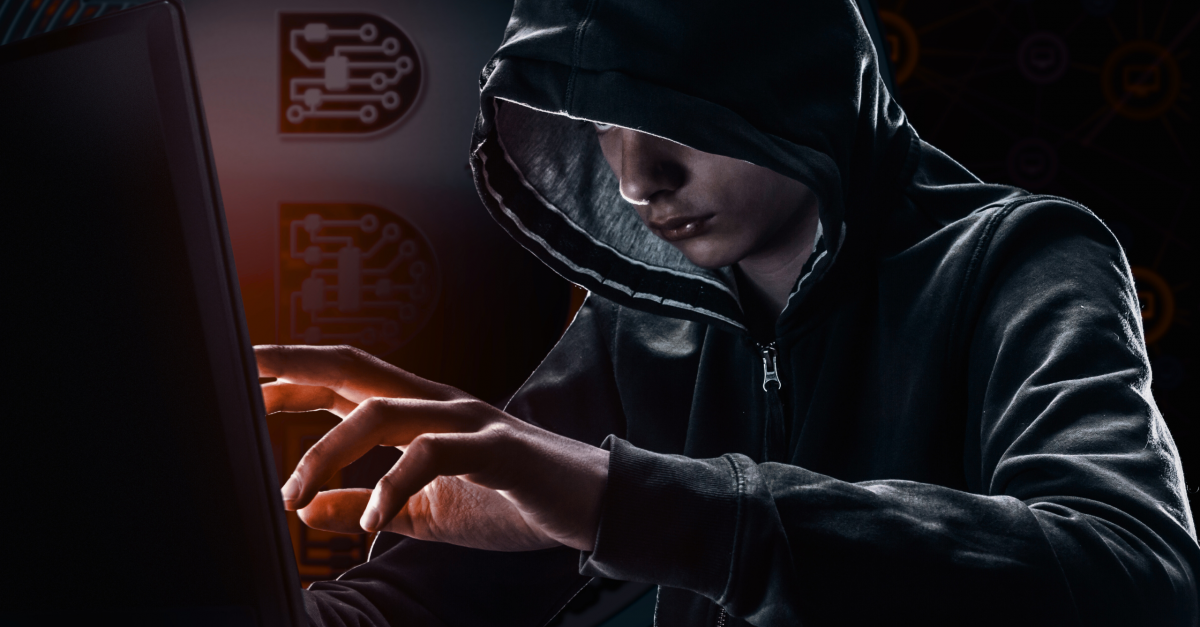 Hacker in a hoodie sitting at a computer